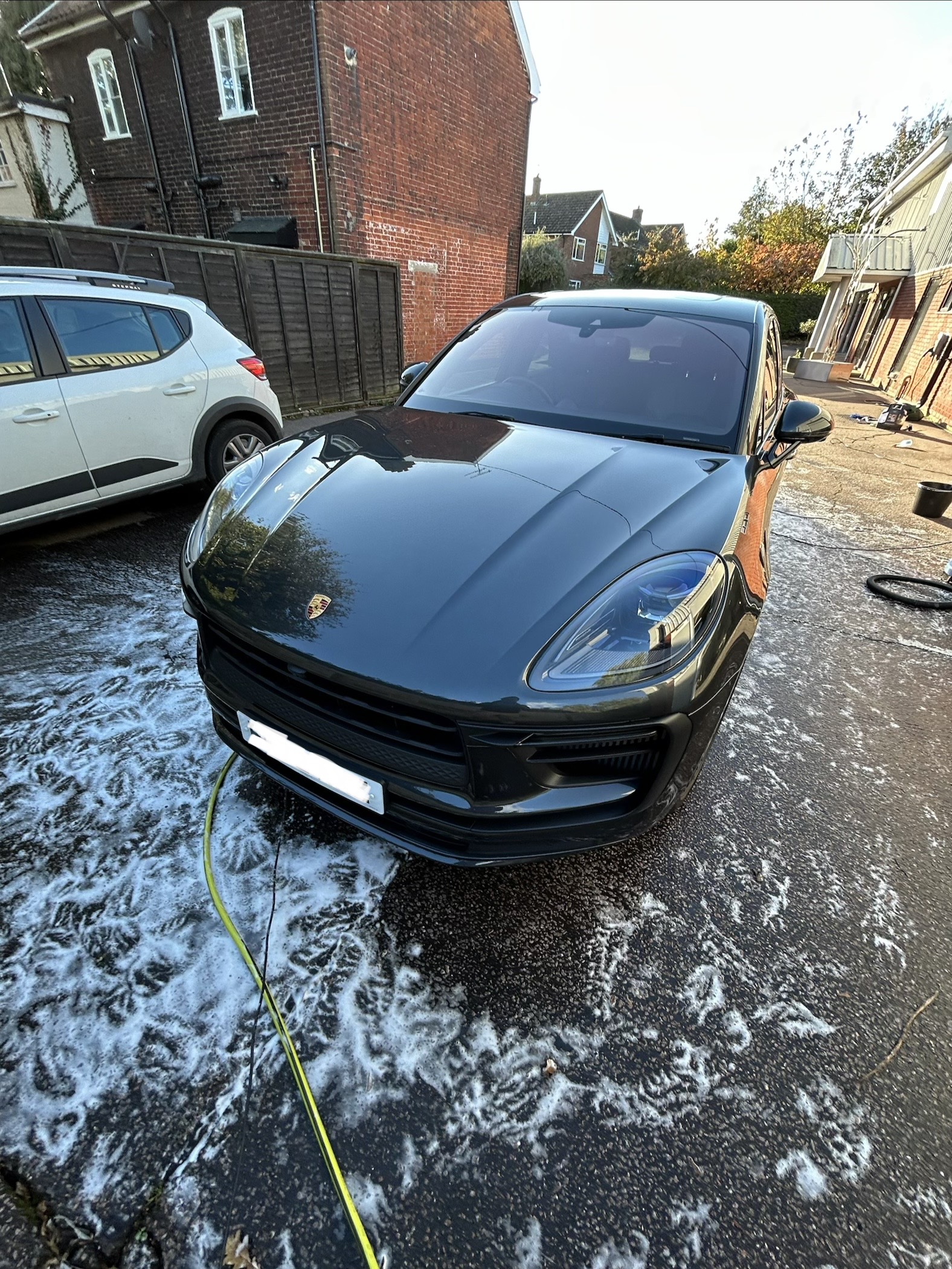 Same dark BMW after detailing — deep mirror gloss, spotless wheels, crystal clear glass